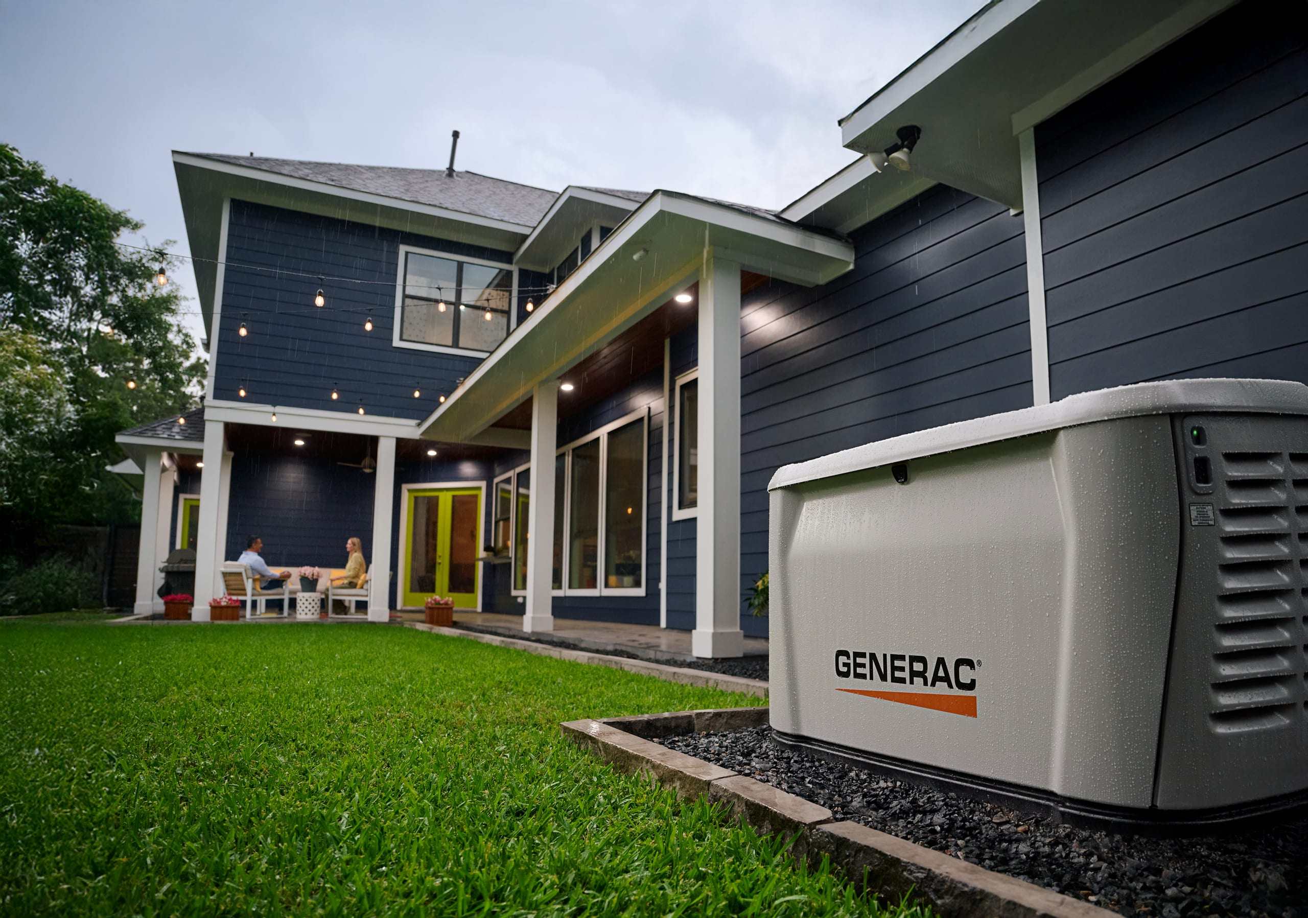 A Generac standby generator installed on a pad beside a home, with the family on the patio behind it